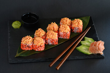 A set of sushi rolls on a wooden board and banana leaf, served with soy sauce, wasabi, ginger, and chopsticks. Perfect for an Asian restaurant menu.