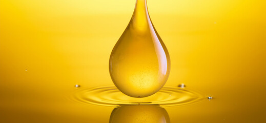 yellow-orange drop of cooking oil falling into water, oil bubbles underwater, yellow background