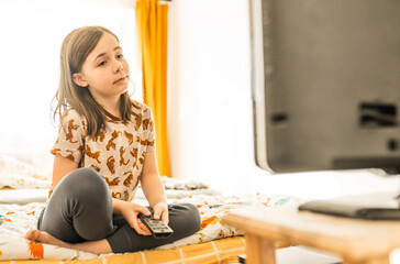 Child watches TV at home. Entertainment for children concept. School girl watches cartoons at home.