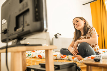 Child watches TV at home. Entertainment for children concept. School girl watches cartoons at home.
