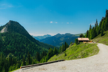 A serene mountain cabin sits on a hillside surrounded by forests and distant mountain peaks