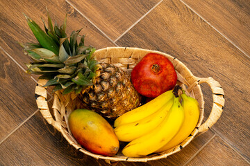 Colorful fruit basket with fresh tropical produce on a wooden floor