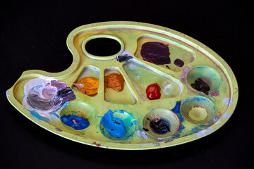 Colorful paint palette with various hues and textures displayed on black