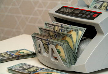 Money counting machine in action with stacks of cash nearby