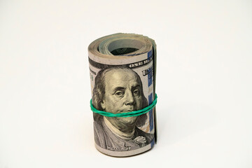 Rolled money banknote secured with a rubber band on a white surface