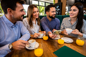 Group of friend met at the cafe. Looking at pictures on the phone. Having fun time together.