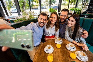 Group of friends at the restaurant taking selfie to capture the moment.