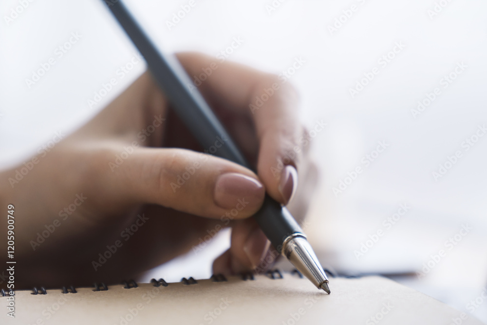 Poster detailed view of a woman's hand jotting notes in a notepad, with a blurred background