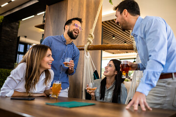 Group of friends met at the restaurant. They hang out, drink beer and laugh.