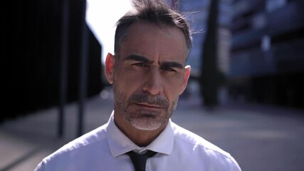 Portrait of a mature businessman looking at camera with confidence standing outside corporative office buildings.