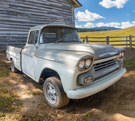 Old pick up parked on a farm next to a barn