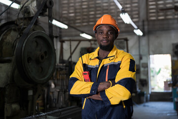 Portrait of African American male engineer standing with crossed arms at industry factory with CNC machine blur background © amorn