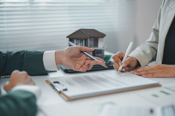 Client signing a contract for a new house, real estate agent pointing at signature place