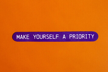 Make yourself a priority message written on purple wooden stick with orange background. Conceptual...