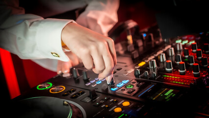 Close up DJ plays live set and mixing music on turntable console in the night club. Disc Jokey Hands on a sound mixer station at club party. DJ mixer controller panel for playing music and partying.