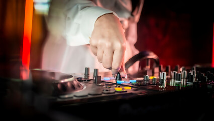 Close up DJ plays live set and mixing music on turntable console in the night club. Disc Jokey Hands on a sound mixer station at club party. DJ mixer controller panel for playing music and partying.