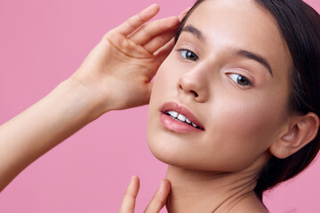 Fototapeta premium Young model with natural beauty showcasing clear skin, delicate features, and a soft expression against a pink background, representing skincare and self care