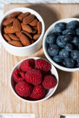 fresh berries and nuts on white table, top view vertical