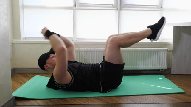 Performing exercises on the abdominal muscles, leg swings during training, Workout at home on a fitness mat, guy in sportswear, slow motion