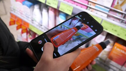 woman hands selects makeup remover and photographs its label via smartphone and sends it to the experts for quality assessment. High quality product selection concept