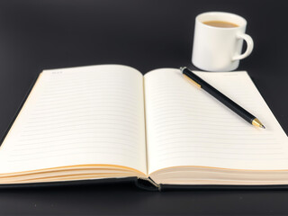 Naklejka premium Blank notebook and pen on a table next to a cup of coffee creating a cozy workspace atmosphere early in the morning