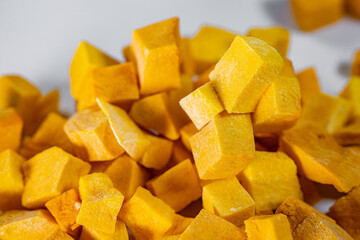 Macro shot of freeze-dried pumpkin cubes showcasing their vibrant orange color and textured surface. Perfect for healthy eating and food preservation themes.