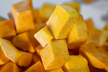 Macro shot of freeze-dried pumpkin cubes showcasing their vibrant orange color and textured surface. Perfect for healthy eating and food preservation themes.