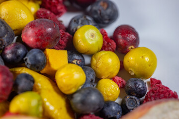 A vibrant mix of freeze-dried blueberries, physalis, cranberries, raspberries, apples, and pumpkin cubes. This colorful assortment showcases a variety of textures and natural colors, perfect for snack