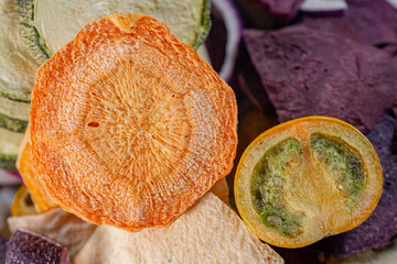 A colorful assortment of freeze-dried vegetables, including bell pepper, red beetroot, carrot, zucchini, onion, and tomato slices. Their vibrant colors and textures highlight their freshness and versa