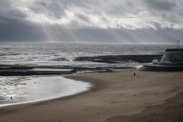 Bay between Broadstairs and Ramgate  in Kent, England with sun rays through the clouds on a cold stormy winters day.