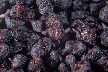 A detailed close-up of freeze-dried honeysuckle berries, showcasing their deep purple hue, wrinkled...
