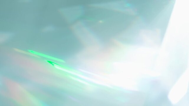 Rainbow Rays of Light in a Prism. Loop. The optical lens system creates a series of bright, changing geometric highlights on a light surface