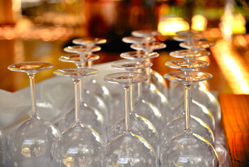 Wine glasses on a bar table. facing downwards. Vibrant warm colors in the background.
