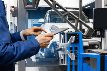Serviceman with digital tablet on the background of the truck in the car service.
