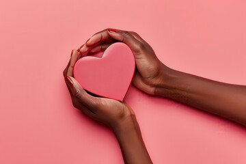 A heart-shaped gift box held in dark skin female hands, set on a soft pink surface for a romantic feel..