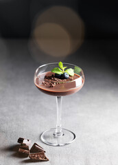 Chocolate pudding in a tall glass with mint  and fresh blueberry on a dark background