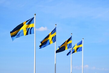 Four Swedish flags flutter against the sky.National Day of Sweden.