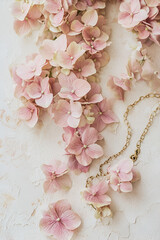 Delicate pink hydrangeas and gold necklace on a textured background. Perfect for wedding invitations or feminine branding.