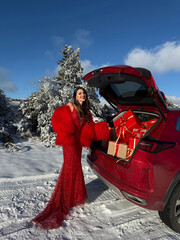 beautiful woman with dark hair in luxurious evening dress with accessories posing in the snowy...
