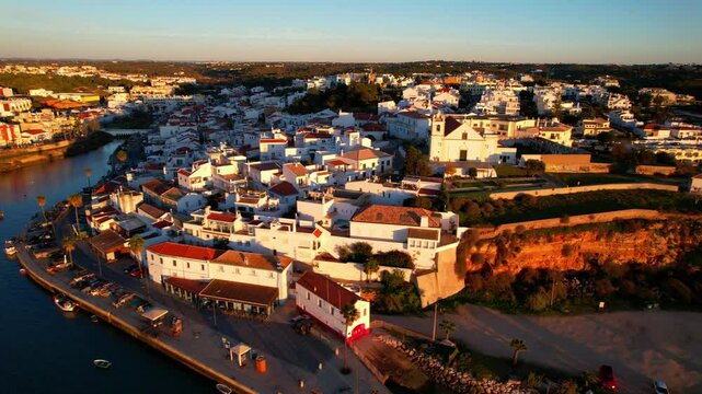  Ferragudo, Portugal: The Prettiest fishing traditional Village in Algarve coast, near Portimao town. aerial high angle video over sunset