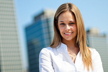 Fototapeta premium Businesswoman smiling with buildings in background