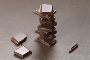 Pieces of dark chocolate on a black wooden background. Close-up