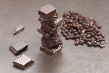 Broken dark chocolate and coffee beans on a wooden table