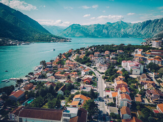 An aerial view of a charming coastal town with red-roofed houses, turquoise waters, and a backdrop...