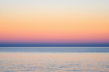 Naklejka premium Sunset Gradient: A sky transitioning from deep orange to soft pink, with the horizon fading into a calm, dusky blue