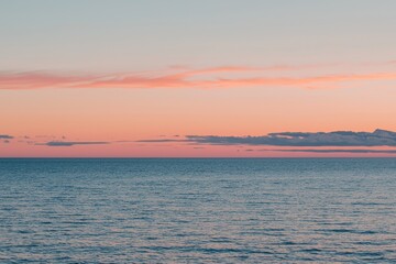 Fototapeta premium Sunset Gradient: A sky transitioning from deep orange to soft pink, with the horizon fading into a calm, dusky blue