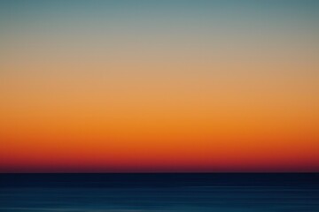 Fototapeta premium Sunset Gradient: A sky transitioning from deep orange to soft pink, with the horizon fading into a calm, dusky blue