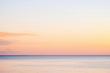 Fototapeta premium Sunset Gradient: A sky transitioning from deep orange to soft pink, with the horizon fading into a calm, dusky blue