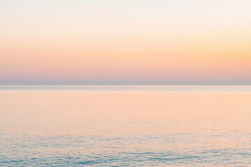 Fototapeta premium Sunset Gradient: A sky transitioning from deep orange to soft pink, with the horizon fading into a calm, dusky blue