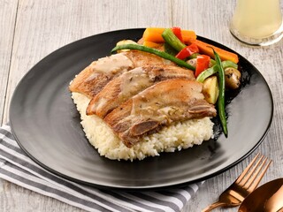 PAN GRILLED PORK BELLY with rice and salad served in dish isolated on wooden table side view of italian fast food